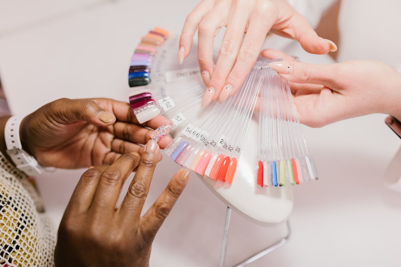 Close-up of hands choosing from a vibrant nail polish sample palette in a salon setting.
